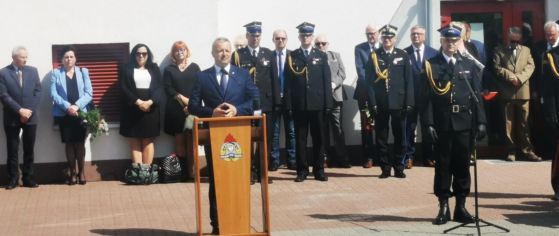 
Grupa ludzi stojąca na placu przed budynkiem
