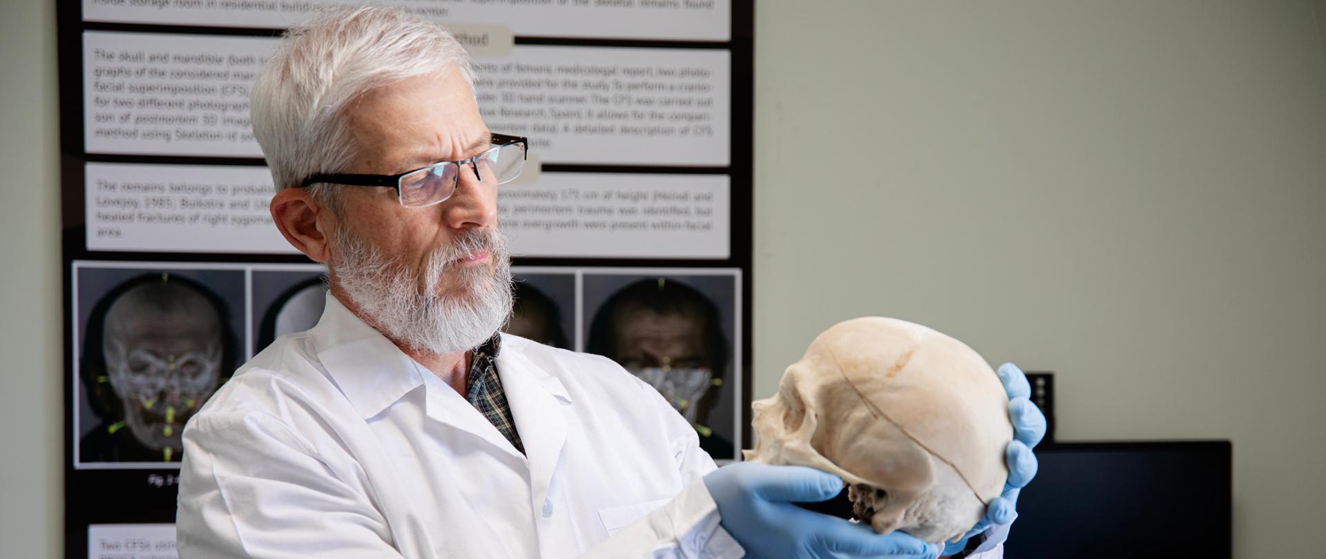 mgr Andrzej Czubak trzymający ludzką czaszkę