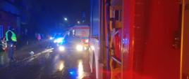 Zdjęcie przedstawia samochód pożarniczy, samochód osobowy i karetkę stojące na ulicy Stefana Batorego w Człuchowie. Na chodniku stoi policjant i dwie osoby postronne, w tle widać strażaków i budynki.