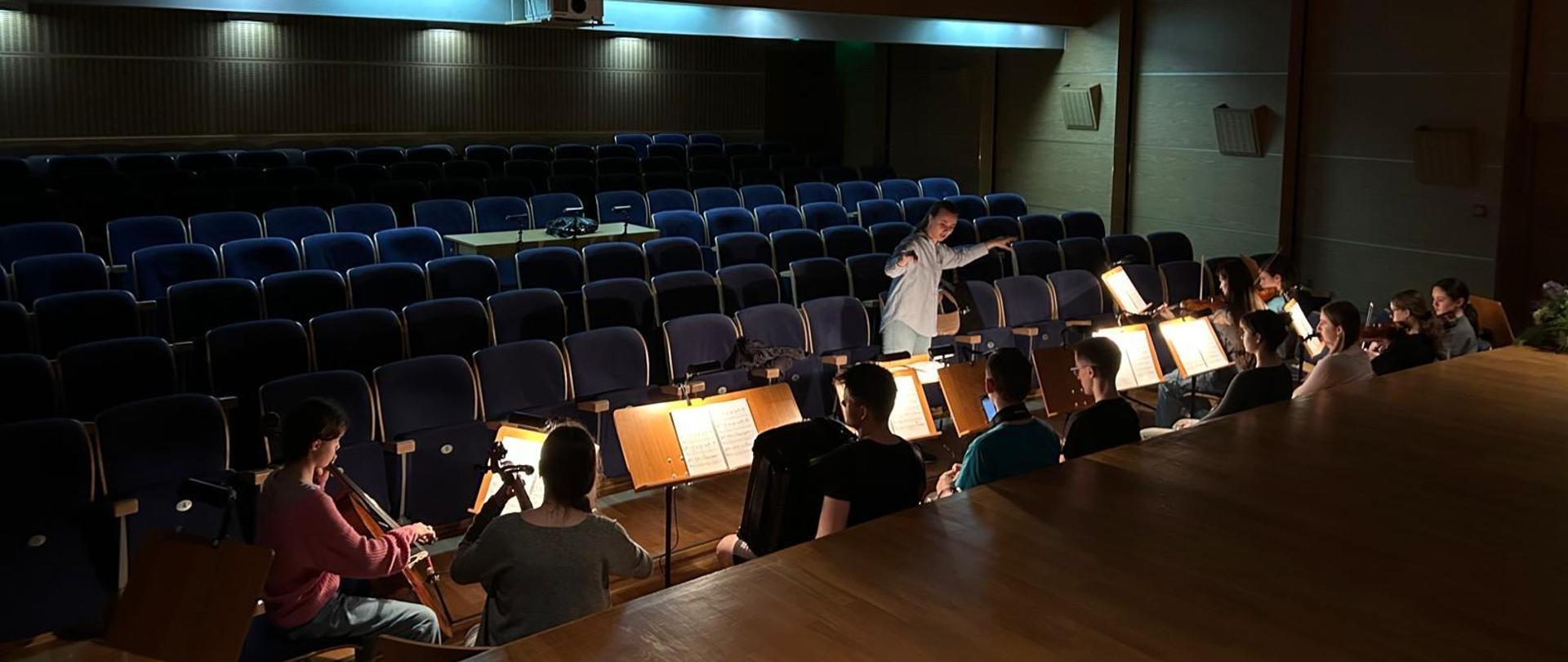 Ujęcie ze sceny - orkiestra ma przy pulpitach zamontowane świecące lampki do nut