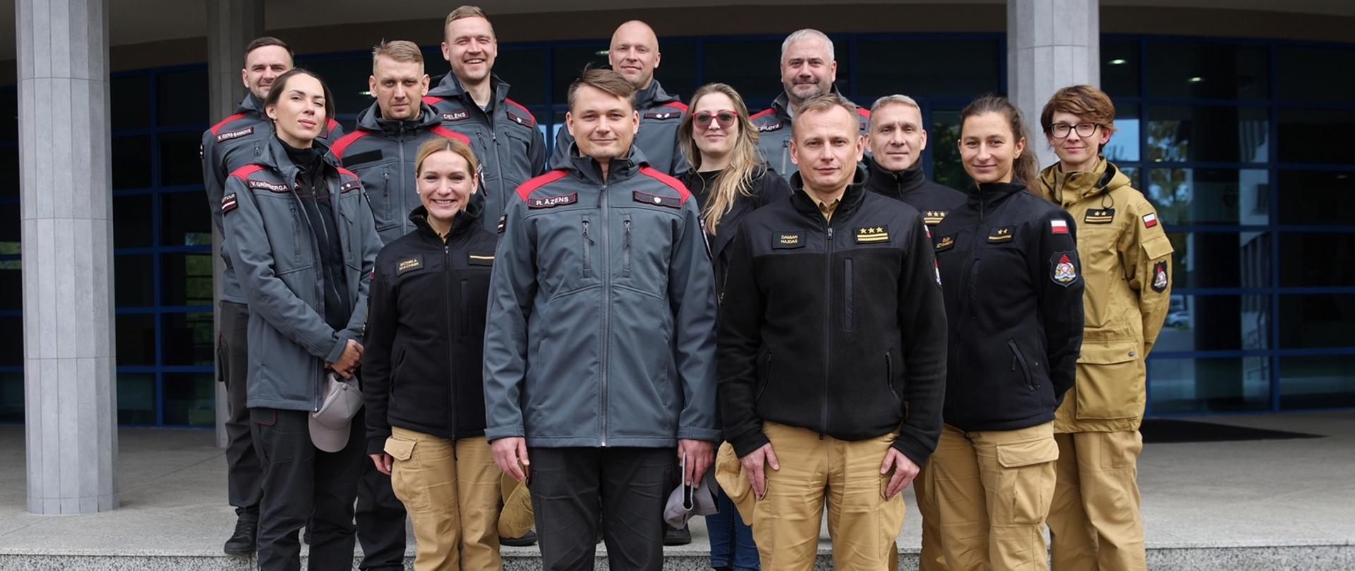 Pamiątkowe zdjęcie funkcjonariuszy delegacji z Łotwy (7 osób) w towarzystwie Zastępcy Komendanta Centralnej Szkoły PSP, kobiety oraz funkcjonariusza CS PSP, dwóch funkcjonariuszek CS PSP oraz funkcjonariuszki PSP