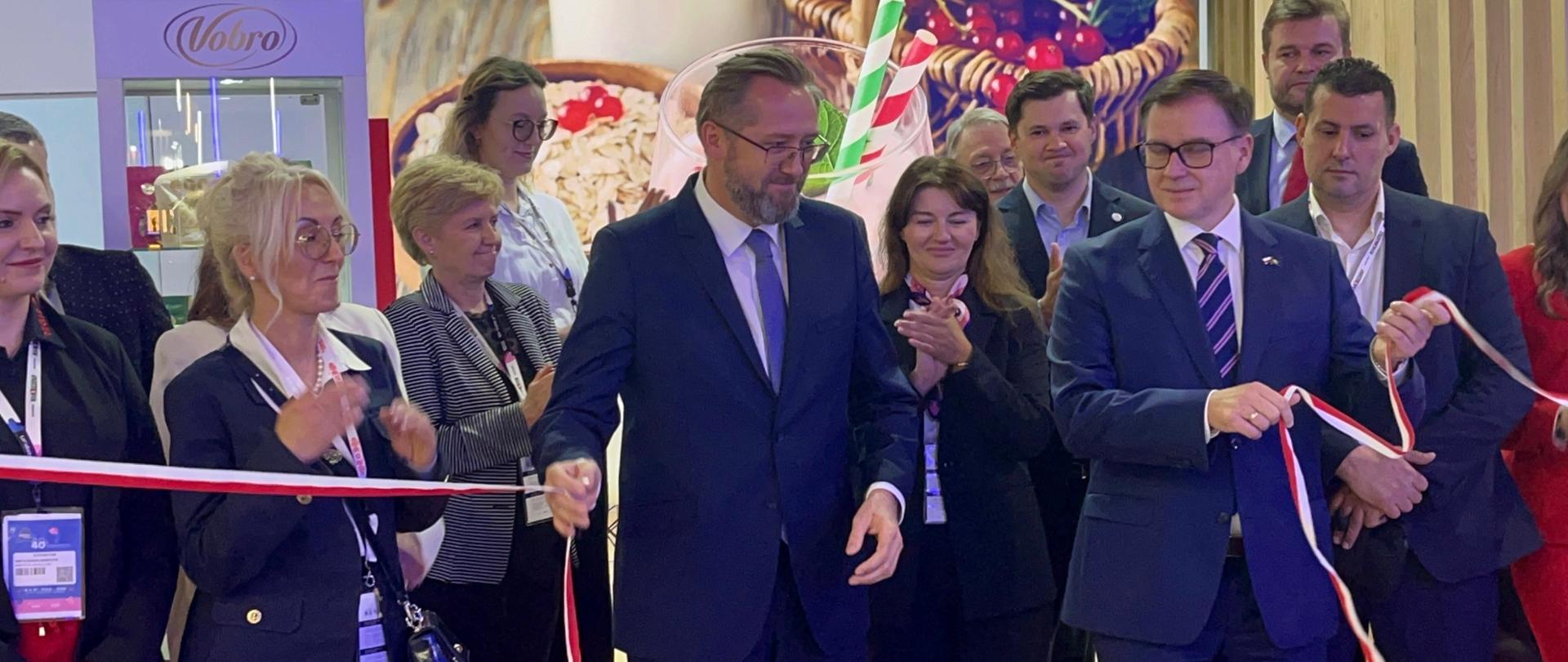 Grupa osób, mężczyzna na pierwszym planie przecina wstęgę