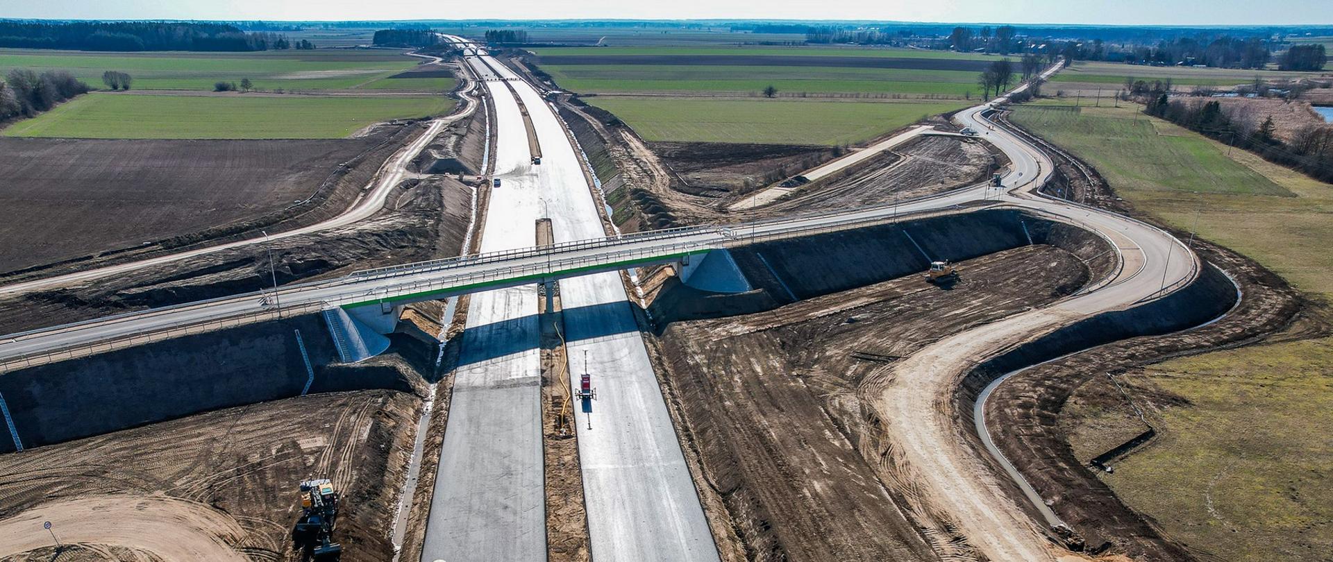 Na pierwszym planie dwie budowane jezdnie drogi ekspresowej S19 na odc. Bielsk Podlaski - Boćki, w poprzek, nad budowanymi jezdniami, gotowy wiadukt drogi powiatowej 