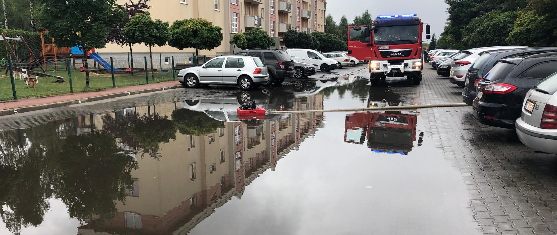 Zdjęcie przedstawia zastęp Państwowej Straży Pożarnej z Jednostki Ratowniczo-Gaśniczej numer 2 podczas działań związanych z zalaną drogą.