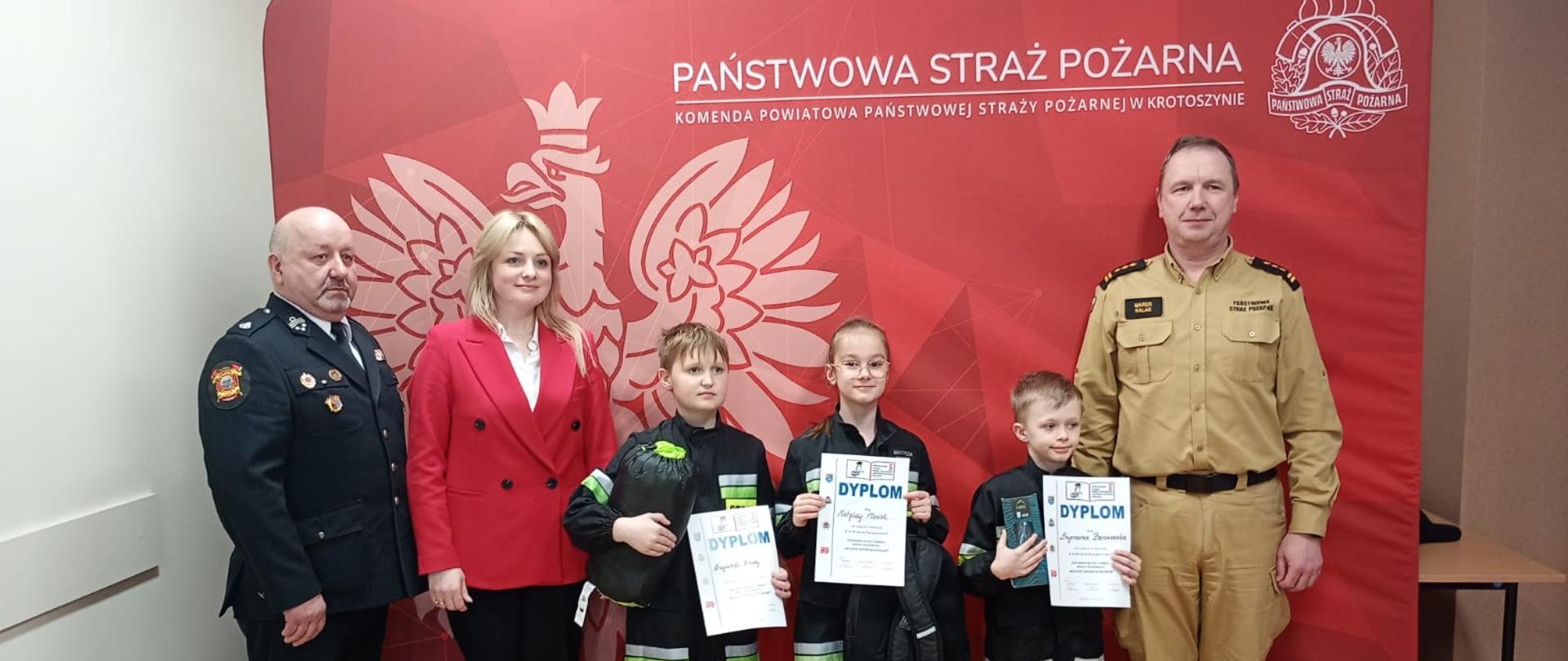 Zdjęcie przedstawia zdjęcie uczestników konkursu pożarniczego wraz z organizatorami konkursu podczas wręczania nagród.