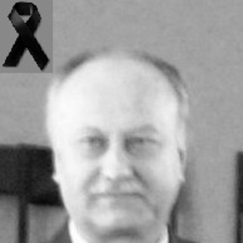 zdjęcie czarno białe przedstawia mężczyznę z wąsem w garniturze w białej koszuli i z krawatem