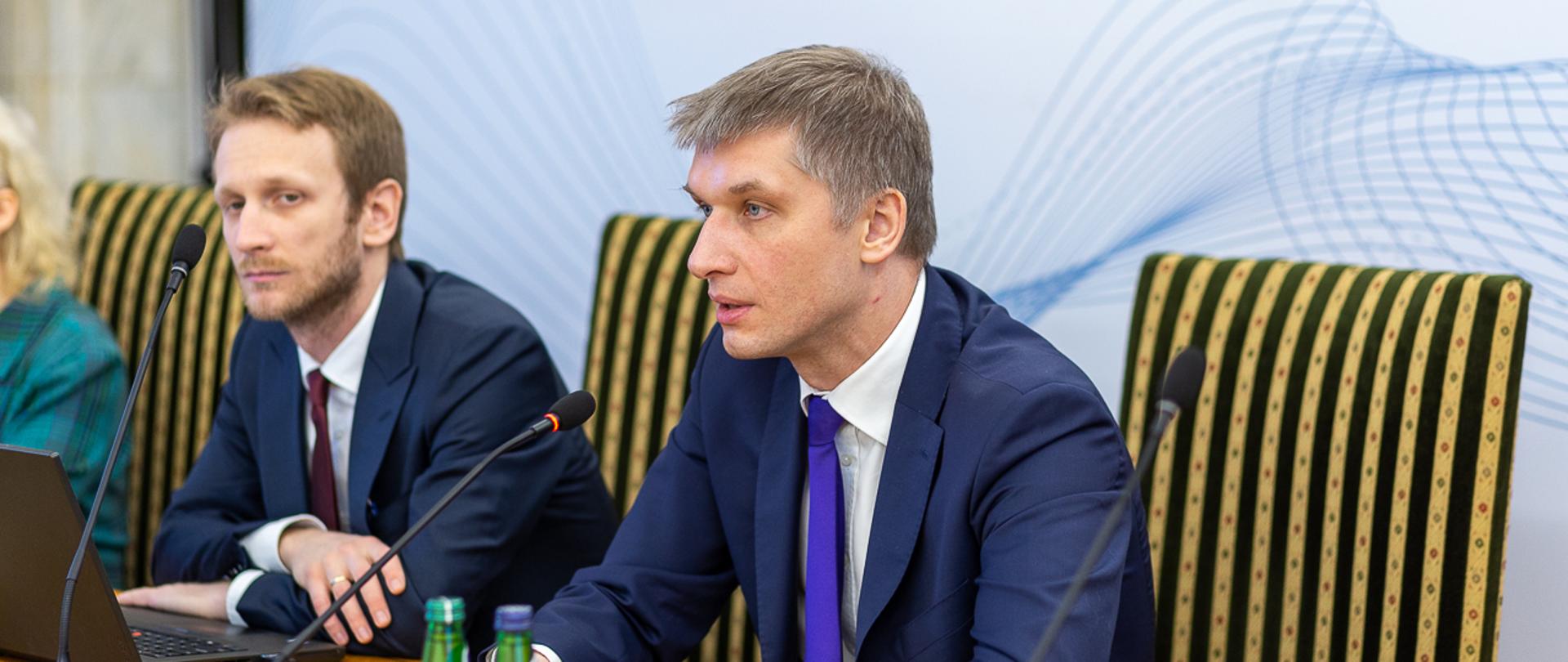 Podsekretarz stanu w MF Piotr Nowak przemawia podczas spotkania do jego uczestników. Obok dyrektor Marcin Obroniecki.