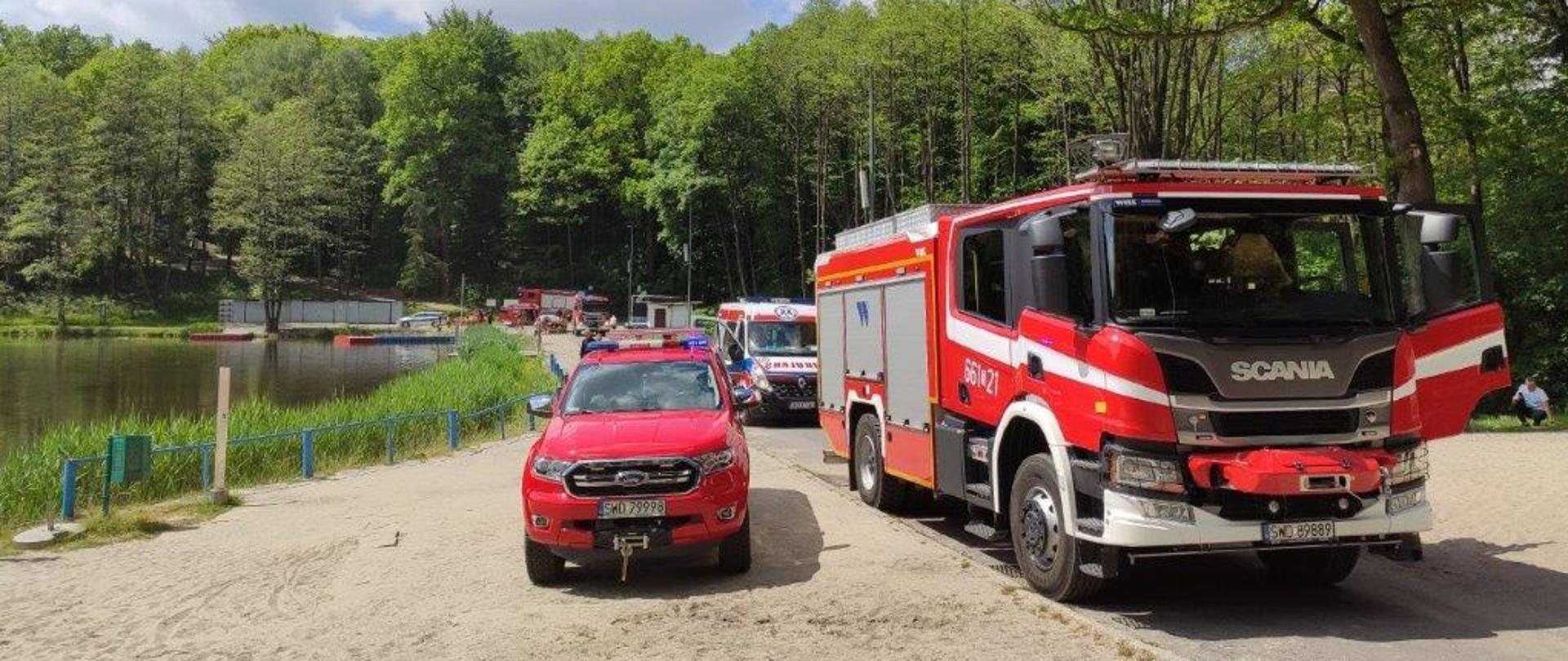 Na zdjęciu samochody pożarnicze na tle zbiornika wodnego na którym poszukiwano mężczyznę
