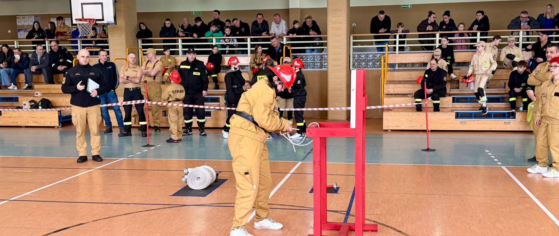 hala sportowa, startujący zawodnik wiąże węzeł, w tle na trybunach publiczność