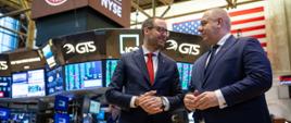 Wicepremier Jacek Sasin i prezes GPW Marek Dietl w hali nowojorskie giełdy. W tle kilkanaście ekranów z danymi