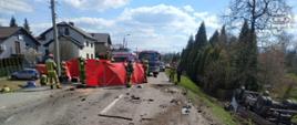 Parawany zasłaniające miejsce wypadku, w rowie leży samochód ciężarowy na dachu, strażacy prowadzą działania na drodze