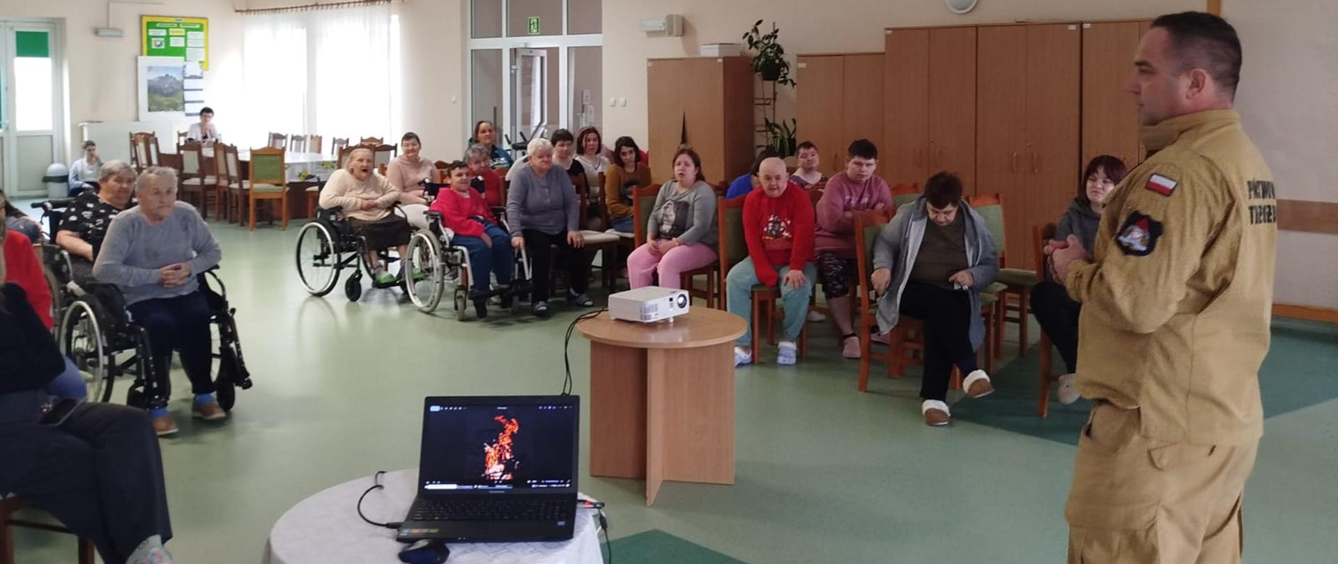 Zdjęcie przedstawia strażaka podczas prelekcji w DPS.