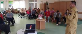 Zdjęcie przedstawia strażaka podczas prelekcji w DPS.