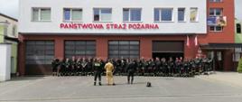 Zdjęcie przed budynkiem komendy. w dwóch rzędach stoją uczestnicy szkolenia w strojach czarnych strażackich . na przeciwko nich stoi trzech funkcjonariuszy straży 