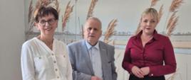 3 osoby w tym mężczyzna w szarym garniturze, pozują do zdjęcia