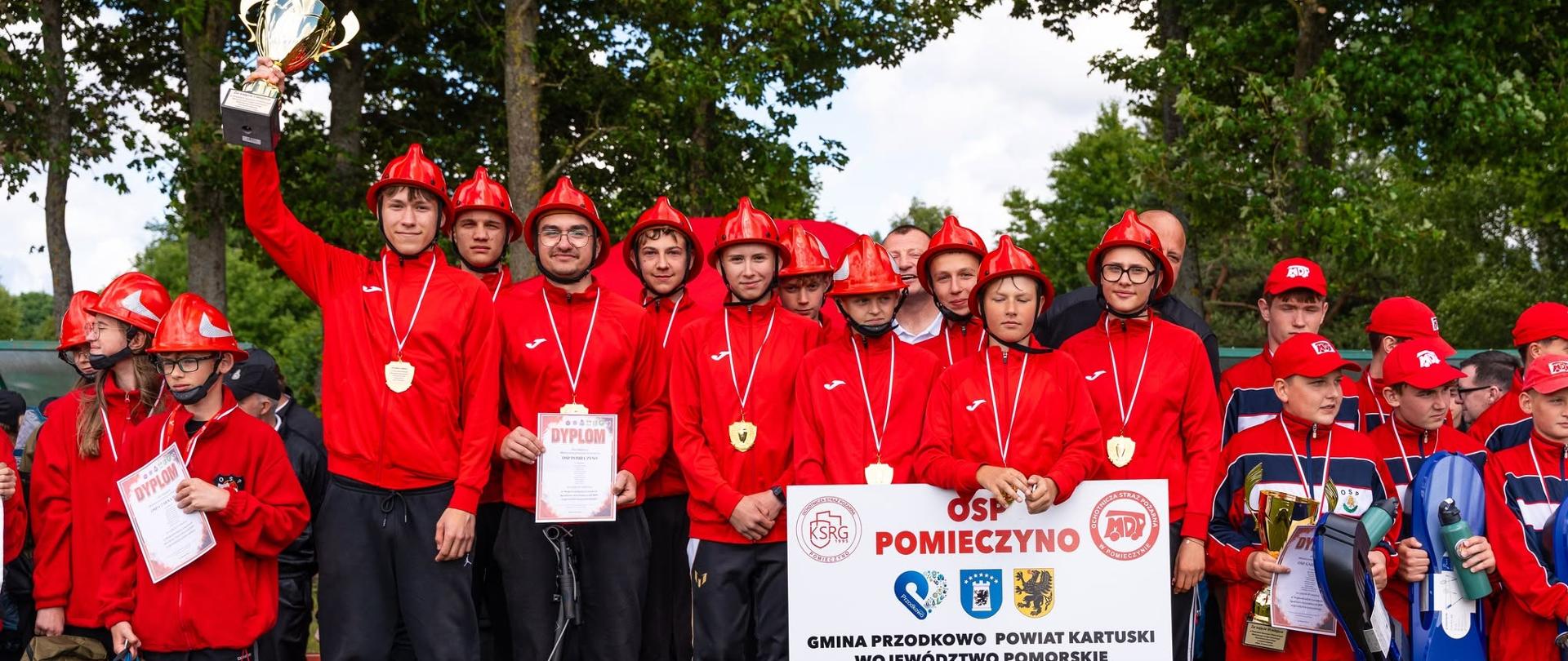 Zdjęcie przedstawia drużynę MDP Pomieczyno stojącą na najwyższym stopniu podium