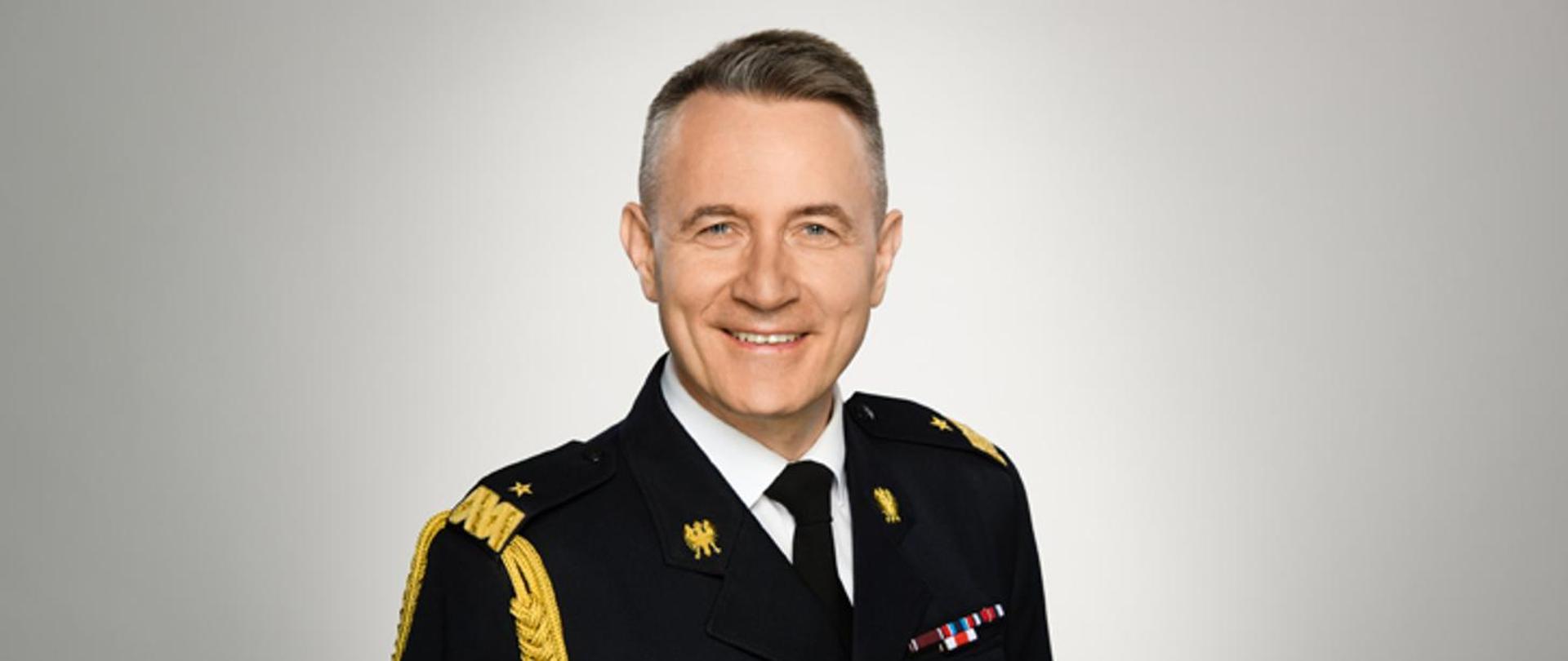 Zdjęcie przestawia Komendanta Głównego PSP w mundurze wyjściowym na szarym tle