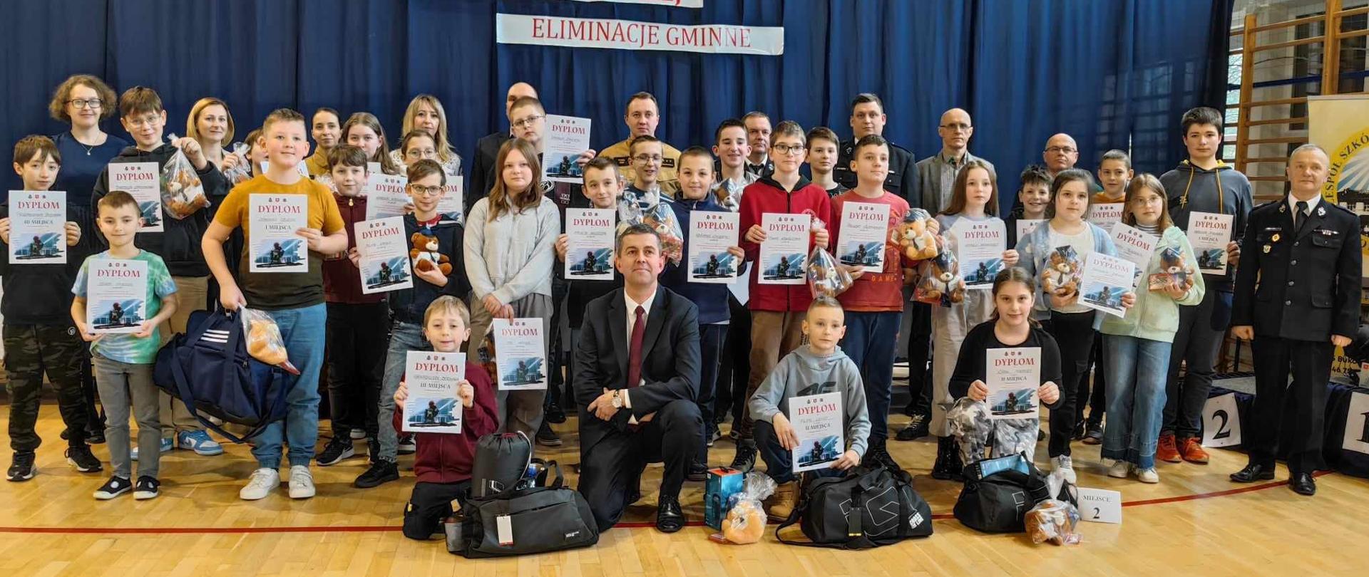 Zdjęcie grupowe wewnątrz sali gimnastycznej. Na zdjęciu około 50 osób., w większości dzieci. 