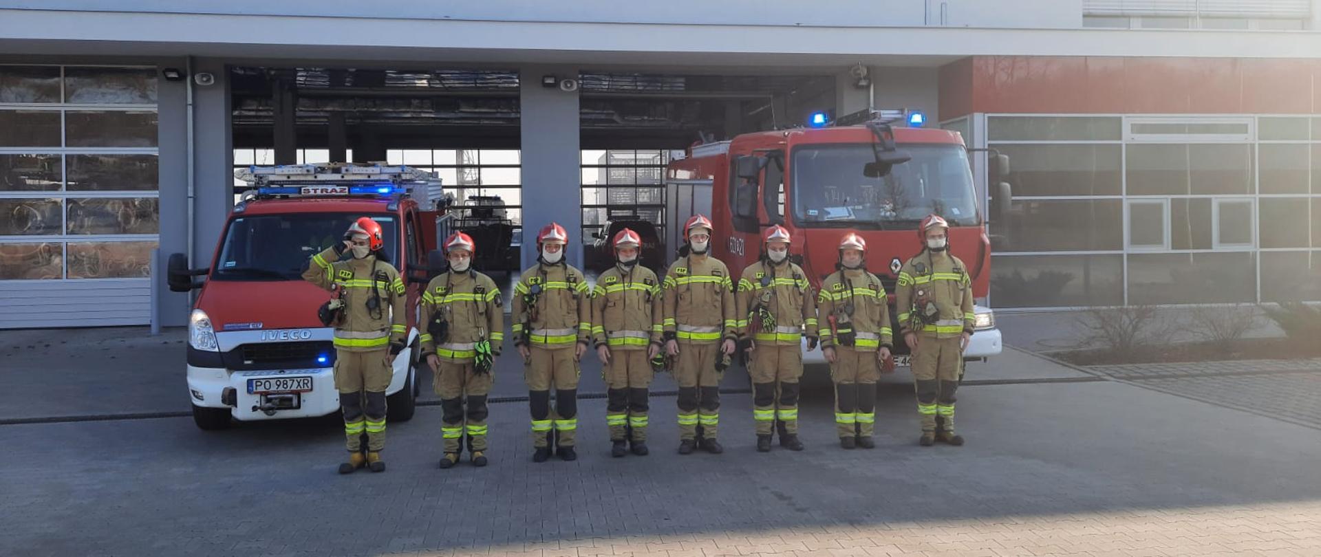 Na zdjęciu strażacy oddający hołd strażakom i ratownikom z ukrainy, umundurowani stoją przed pojazdami które mają włączone sygnały świetlne