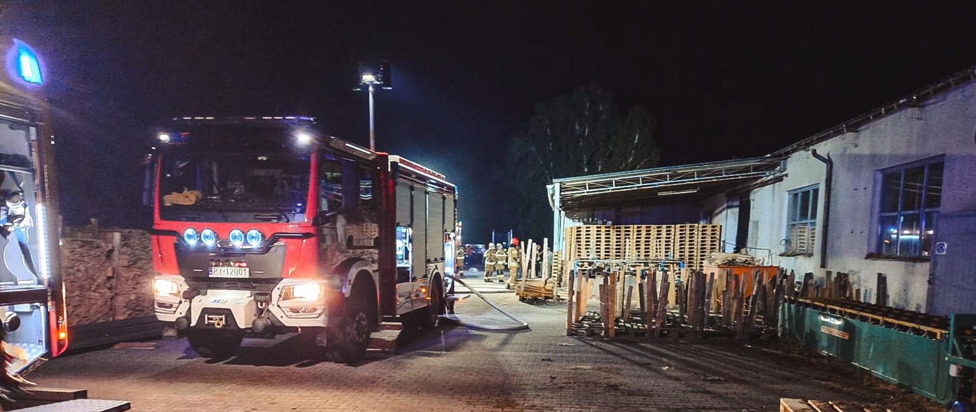 Samochody strażackie stojące na terenie zakładu. Zdjęcie wykonane w porze nocnej.