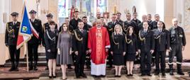Strażacy stoja w raz z kapelanem w kościele.