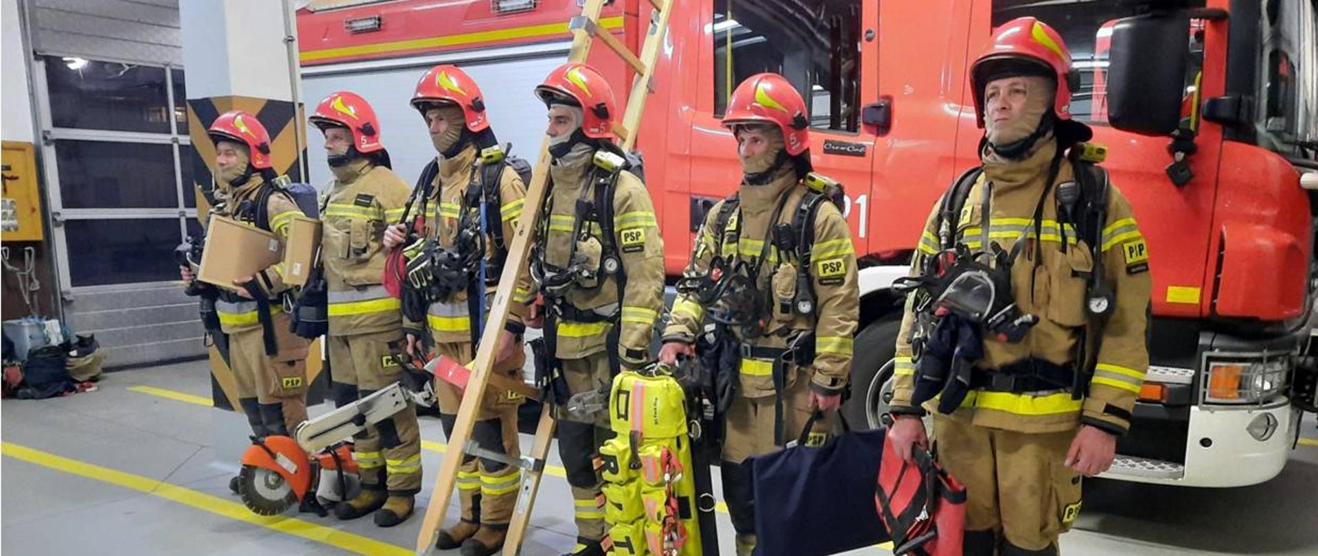 Zastęp ze sprzętem w ubraniach specjalnych stojący w szeregu