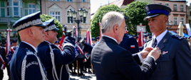 Wojewoda pomorski w obecności przedstawicieli Policji przypina wyróżnienie policjantowi.