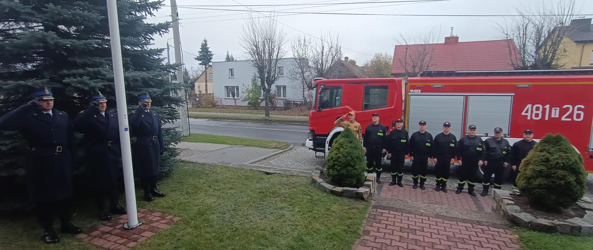 Strażacy wciągnęli flagę na maszt i śpiewają hymn Państwowy