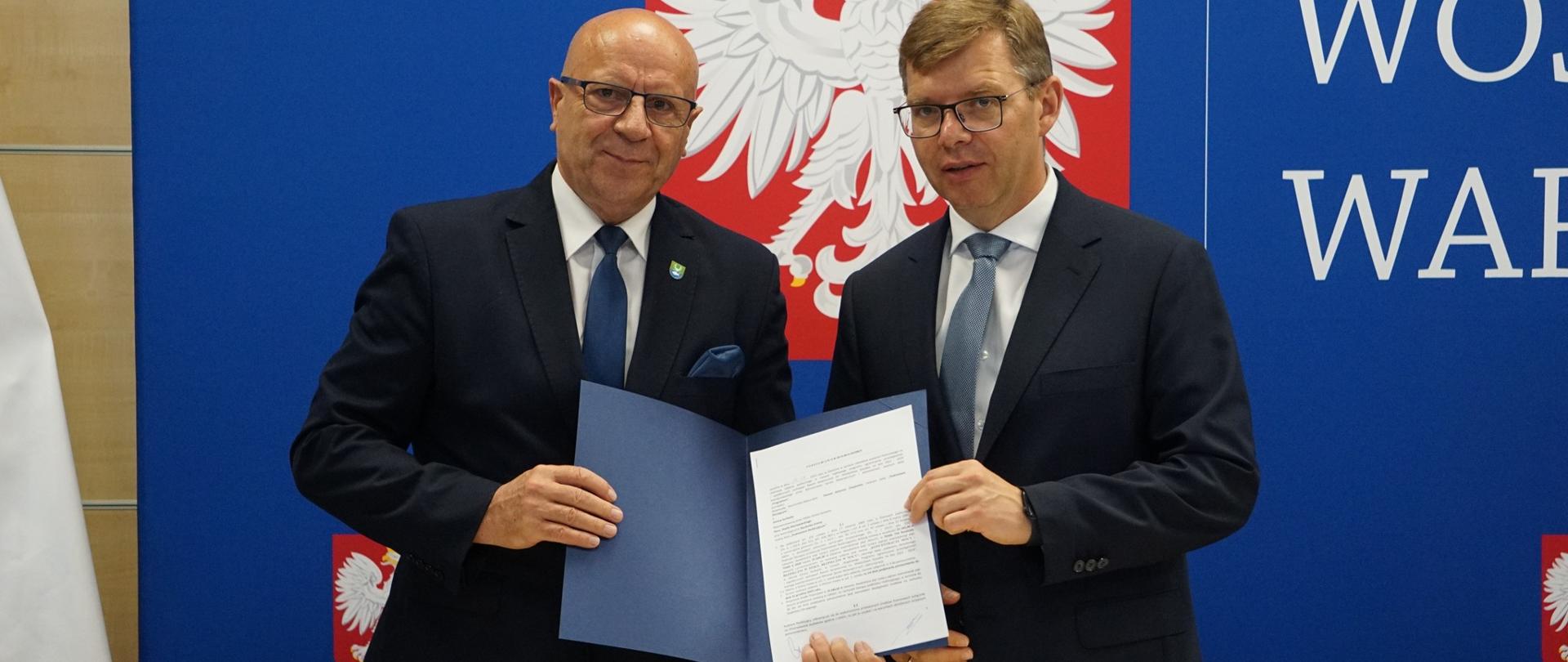 Wojewoda stoi z mężczyzną i pokazują podpisana umowę 