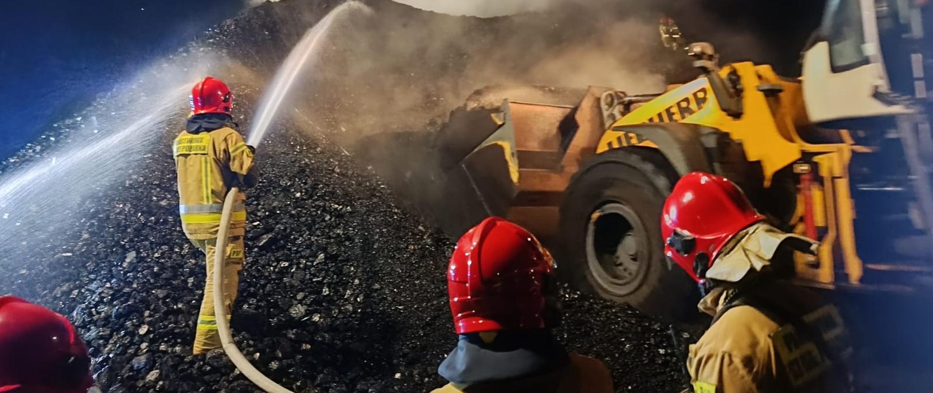 Na zdjęciu widać strażaków podczas działań gaśniczych, jest noc. 