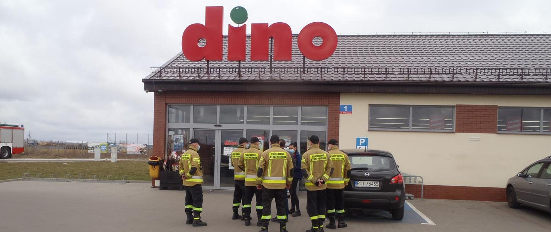 Strażacy stojący przed sklepem DION 
