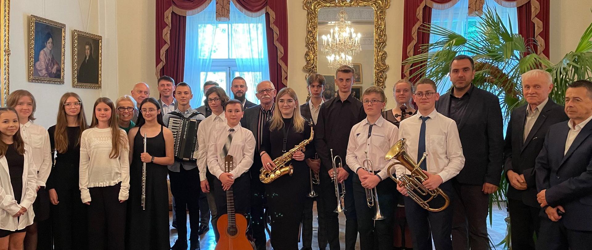 Grupa uczniów kończących szkołę z instrumentami w Sali Balowej pałacu Lubomirskich w Przeworsku.