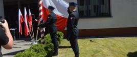 Plac przed komendą. Poczet flagowy dokonuje podniesienia flagi państwowej na maszt.