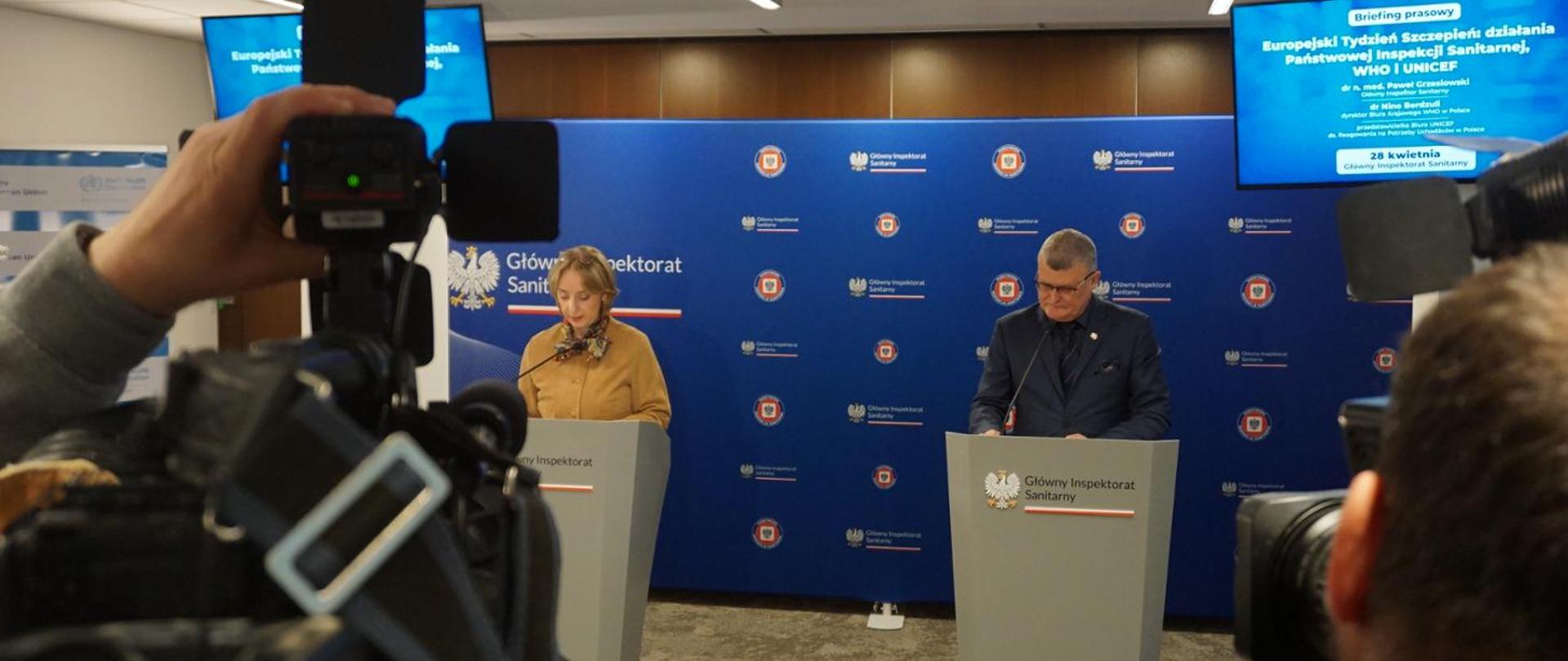 Konferencja prasowa: na ściance z logiem Państwowej Inspekcji Sanitarnej przemawiają Nino Berdzuli, Dyrektor Biura WHO w Polsce oraz Paweł Grzesiowski Główny Inspektor Sanitarny