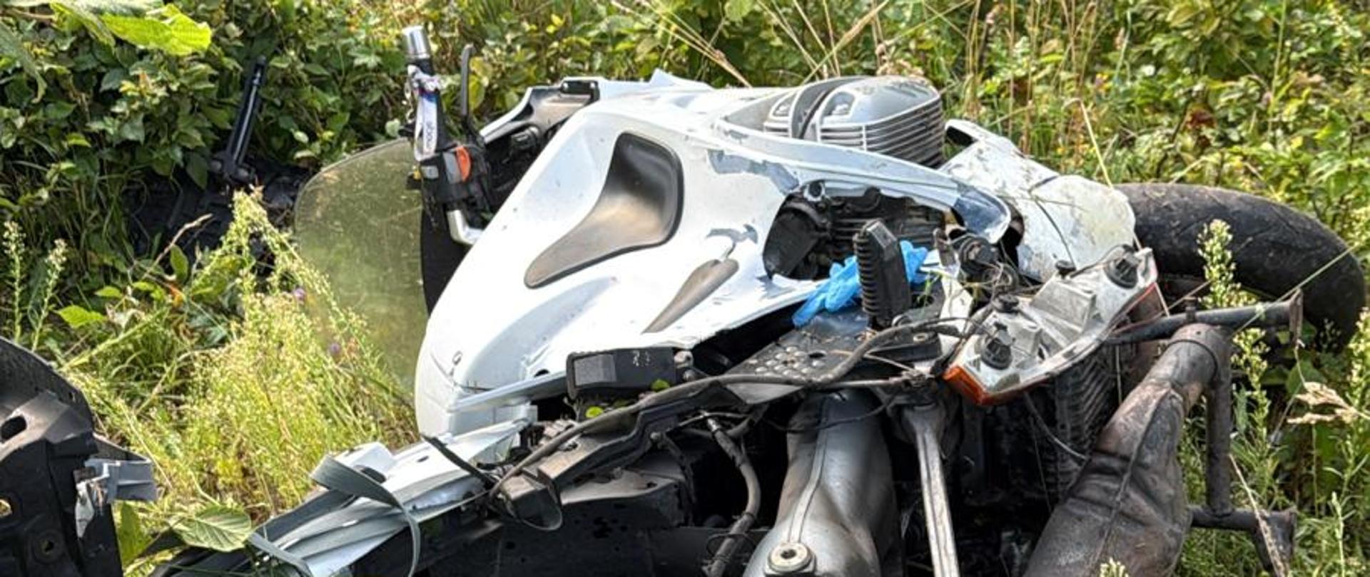 Zniszczony motor w rowie, leży na trawie.