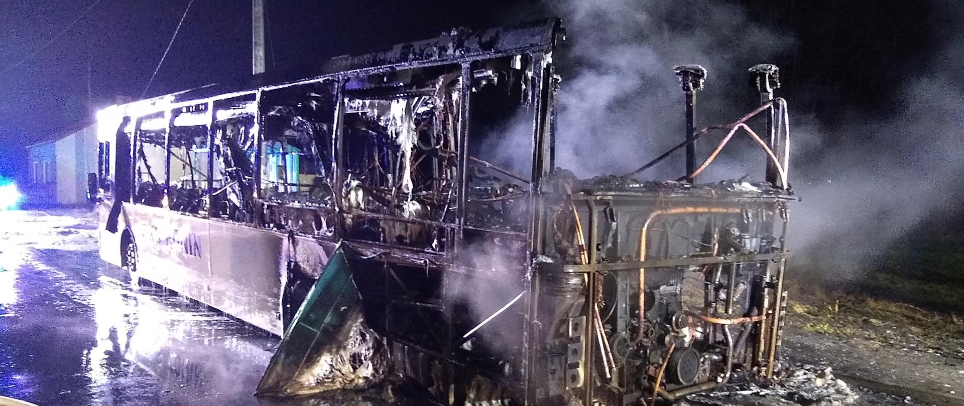 Zdjęcie przedstawia spalony autobus zaparkowany na zatoczce autobusowej
