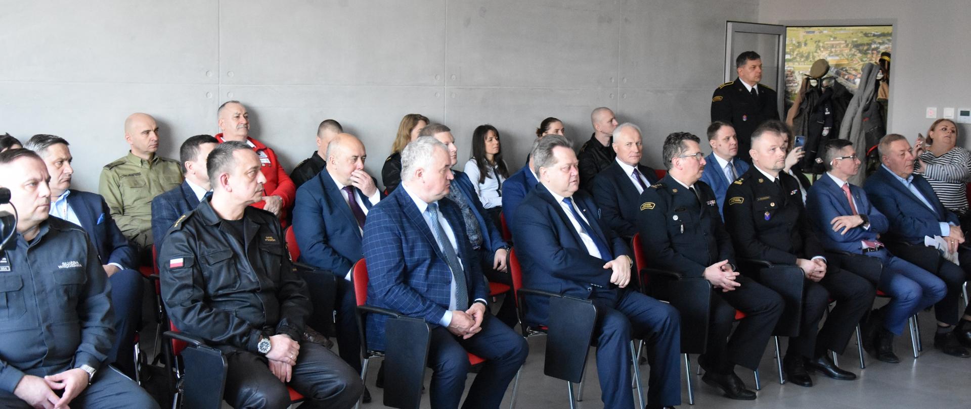 Osoby zaproszone siedzą na krzesełkach w sali narad KM PSP w Suwałkach