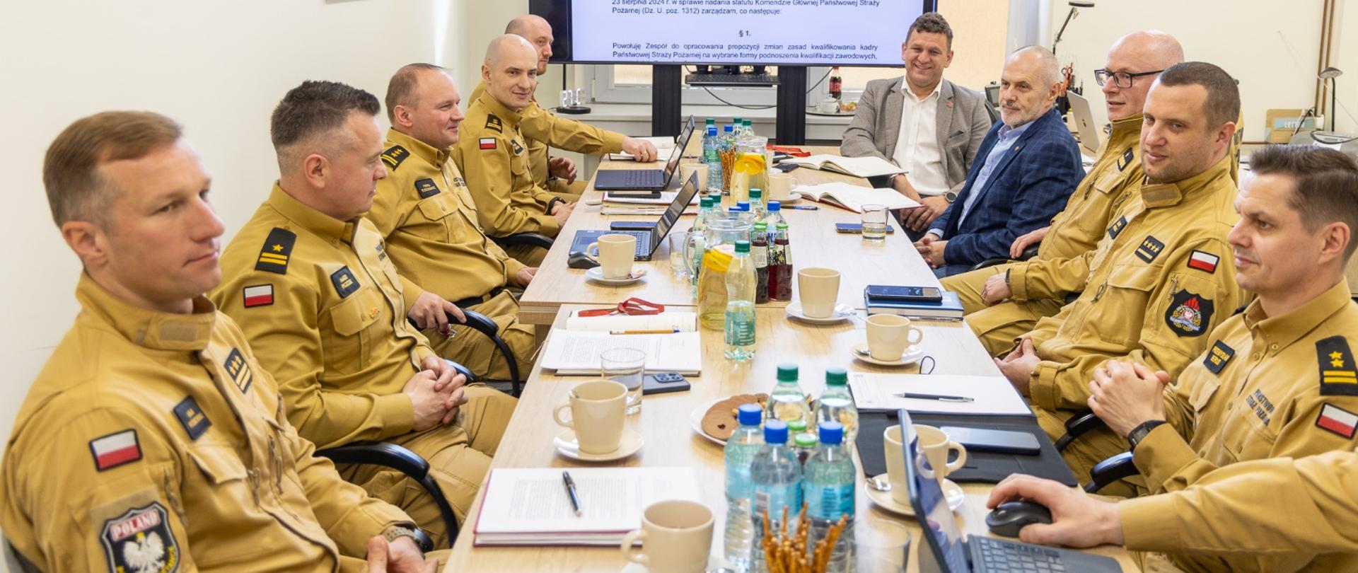 Grupa ludzi siędząca przy stole. funkcjonariusze i cywile.