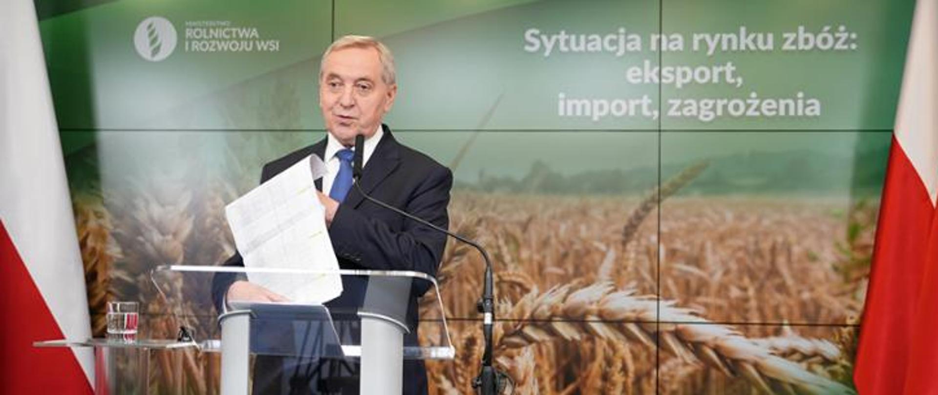 Mężczyzna na tle bannera z napisem "Sytuacja na rynku zbóż: eksport, import, zagrożenia"