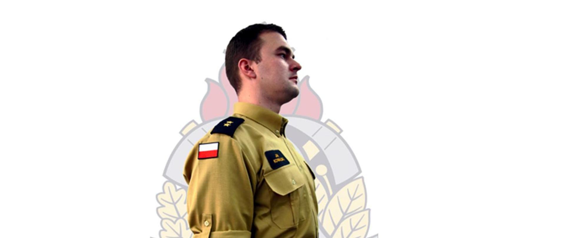 Strażak w prawym profilu na tle logo psp, w nowym umundurowaniu koloru piaskowego> elementy munduru - koszula z krótki rękawem z czarnymi pagonam 