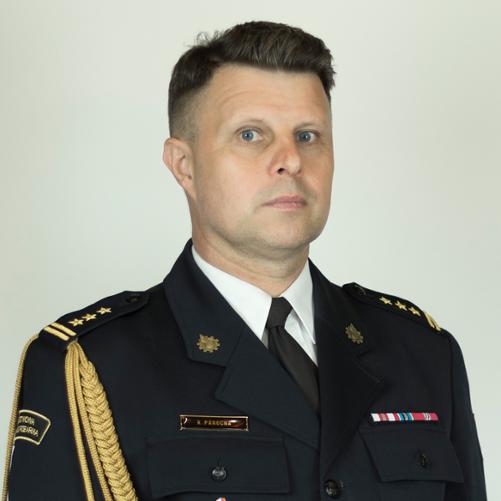 Zdjęcie przedstawia Komendanta Powiatowego PSP w Górze. Jest to portret w ciemnym mundurze strażackim na jasnoszarym tle. Na mundurze widoczne są oznaczenia stopnia, odznaczenia oraz tabliczka z nazwiskiem „K. Panocha”. Na lewym ramieniu znajduje się ozdobny złoty sznur.”