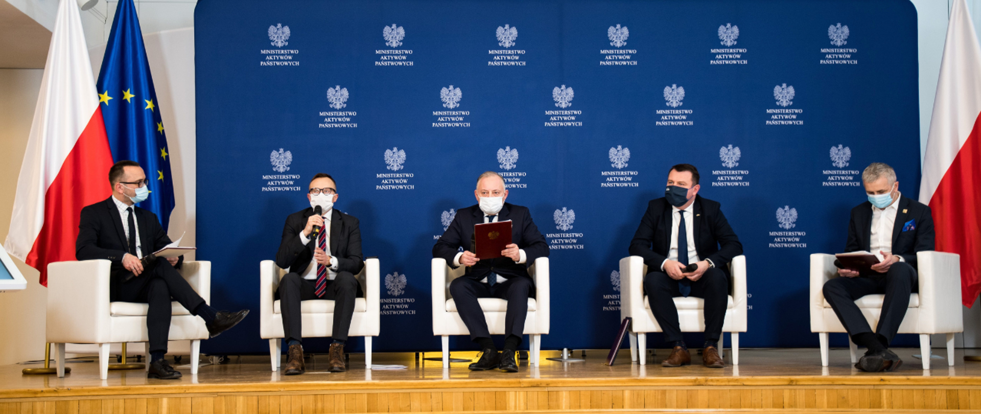 Uczestnicy Forum MAP siedzą w fotelach podczas debaty. W tle ścianka z logotypami MAP i flagi polskie i unijna.