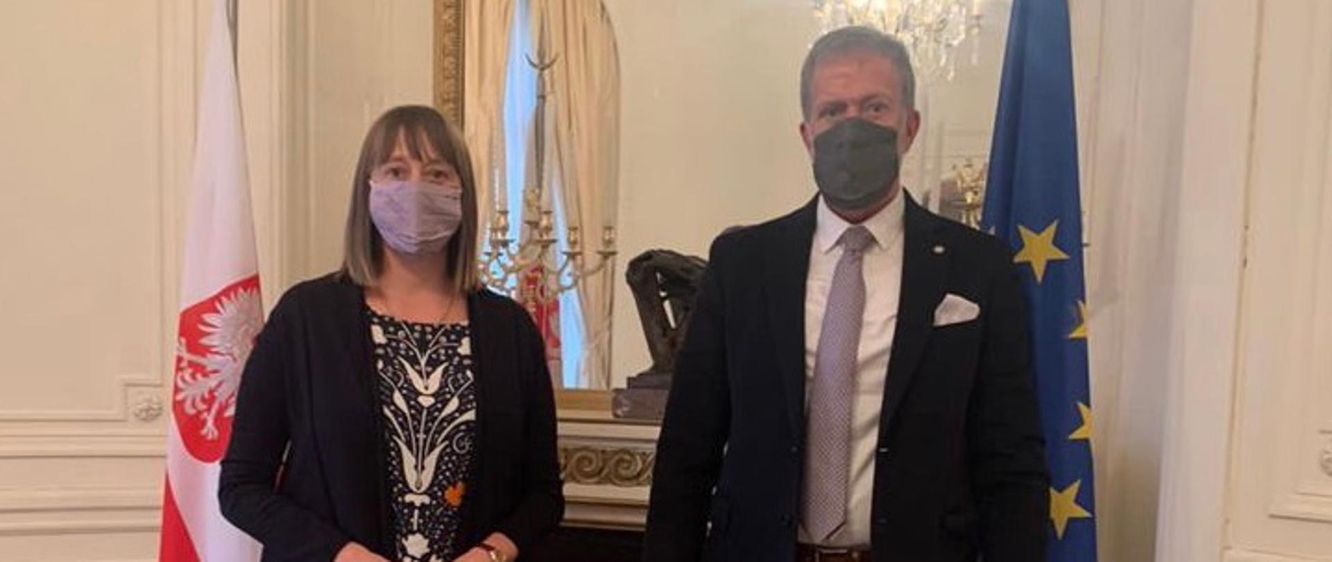 Spotkanie dwóch osób na tle flag