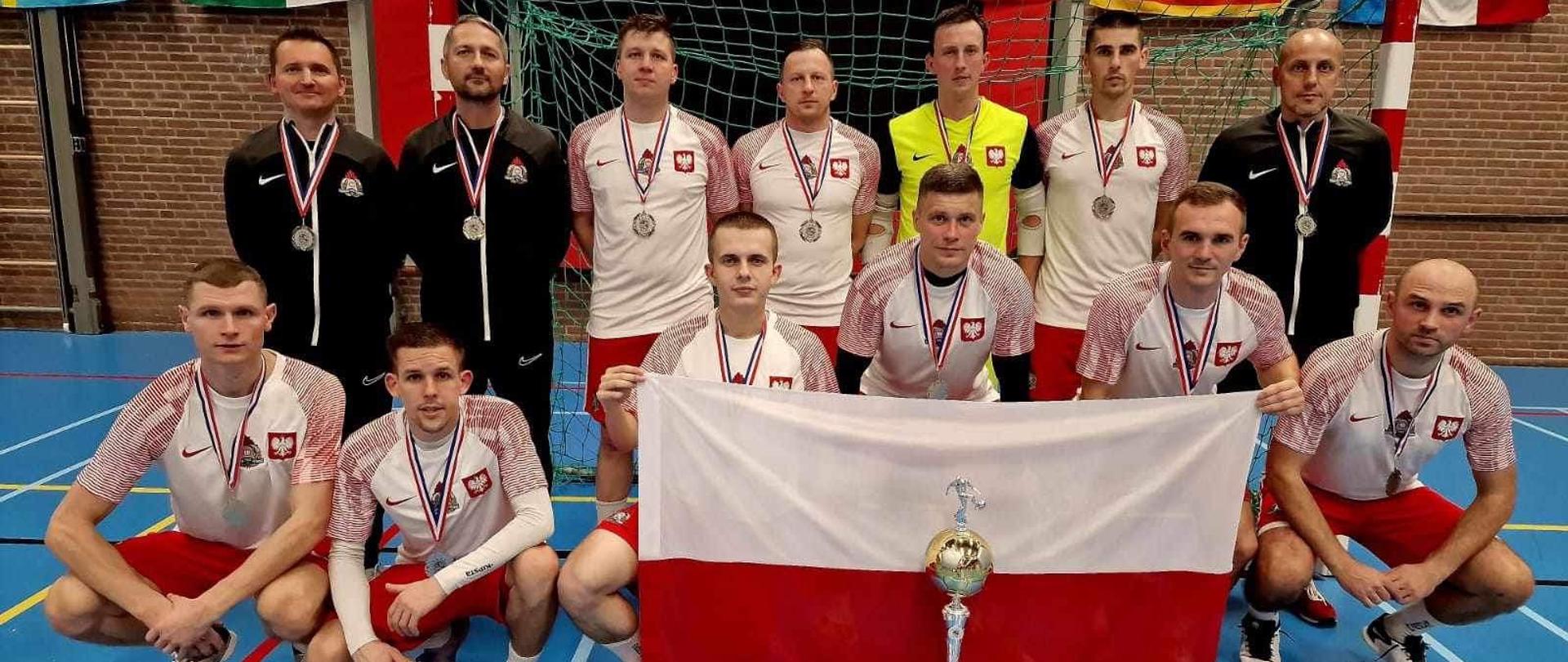 Zawodnicy z flagą polski na sali sportowej.