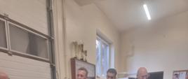 Zdjęcie przedstawia Zastępcę Wielkopolskiego Komendanta Wojewódzkiego podczas rozmowy ze strażakami OSP Miłosław w garażu