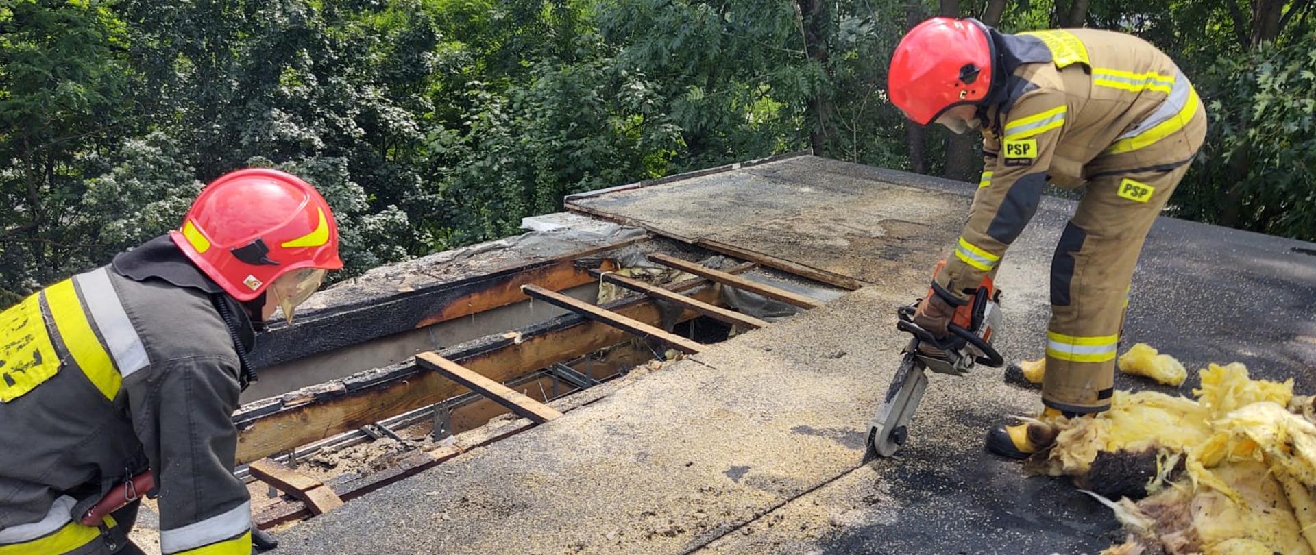 Strażacy przy pomocy piły wycinają fragment dachu.