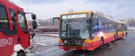 Na zdjęciu widoczny jest autobus który brał udział w wypadku, ma rozbity przód. Obok stoi wóz straży pożarnej.
