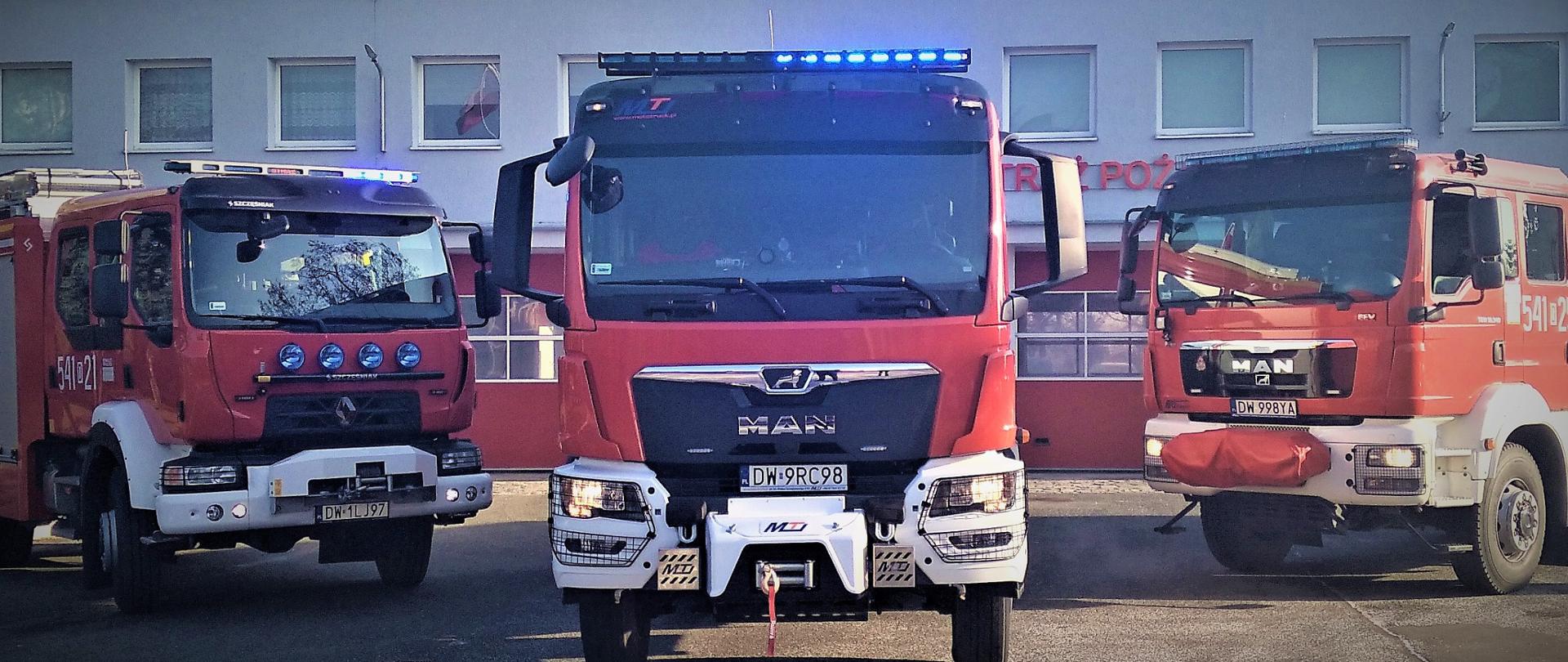 Samochody pożarnicze na tle budynku komendy.