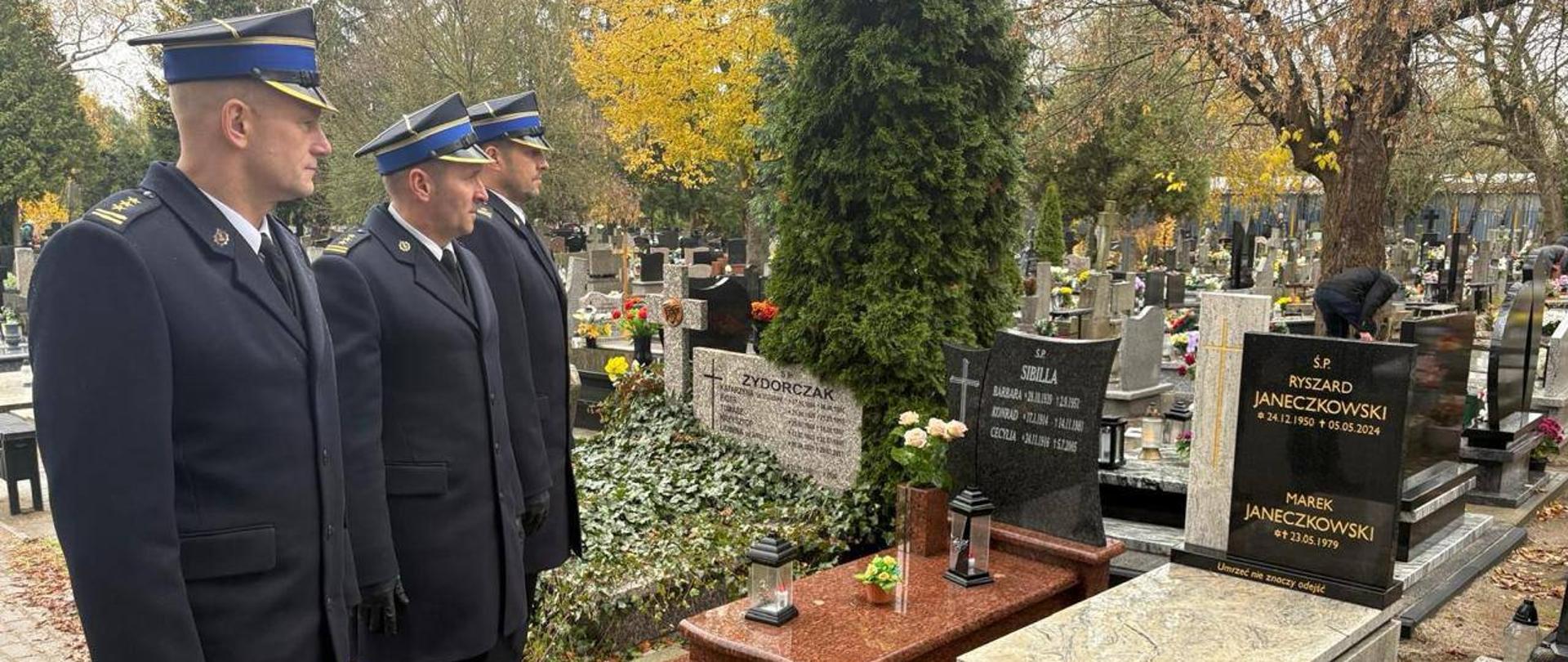 Komendant Miejski st. bryg. Tomasz Czajka wraz z Zastępcami stoją przy jednym z grobów. Grób byłego Komendanta Ryszarda Janeczkowskiego.