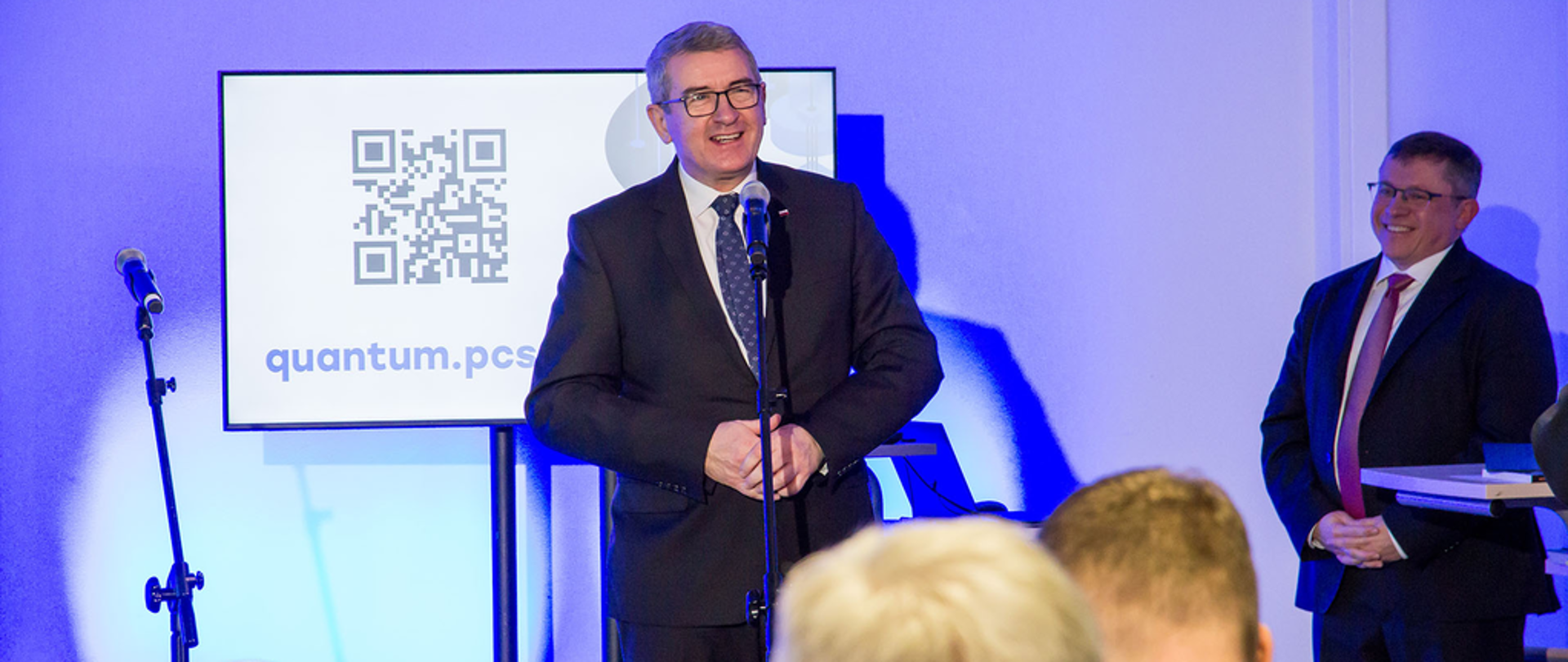 wiceminister Wojciech Murdzek przemawia do mikrofonu podczas wystąpienia na otwarciu hubu do obliczeń kwantowych na politechnice w Poznaniu